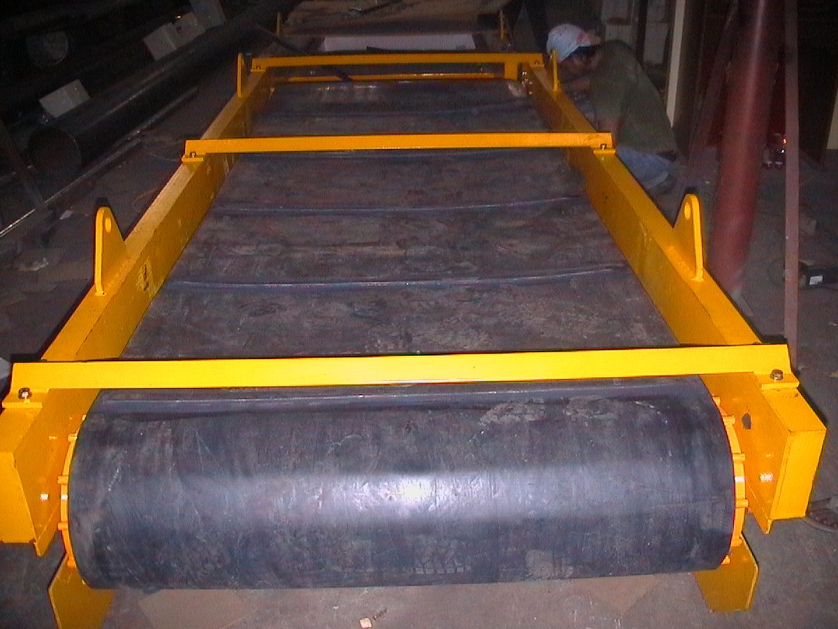 Self-cleaning overband magnet with wide black belt and yellow side rails, seen along its length